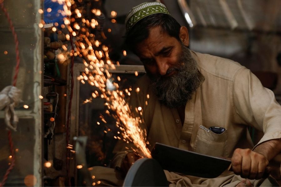 Seorang pandai besi mengasah parang pada malam Idul Adha di Peshawar, Pakistan, 9 Juli 2022.