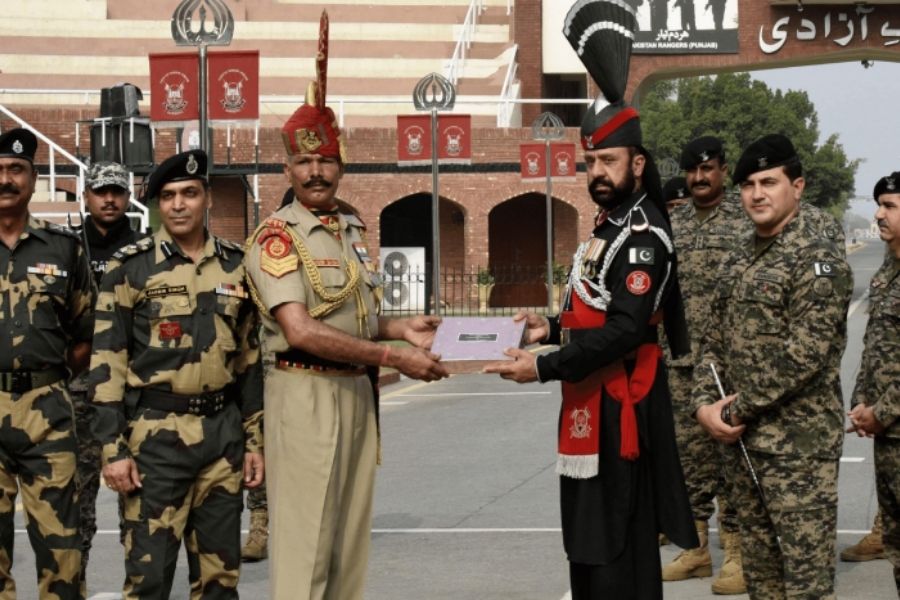 Prajurit Pasukan Keamanan Perbatasan India (BSF) (tengah kiri) menerima permen dari tentara Rangers Pakistan (tengah kanan) pada kesempatan Idul Adha di pos perbatasan India-Pakistan Wagah.  — AFP