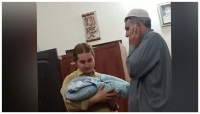 Entertainer Nasir Khan Jan holds his baby boy while an elderly person recites the Azan. — Screengrab via Instagram/nasirkhanjanofficial_