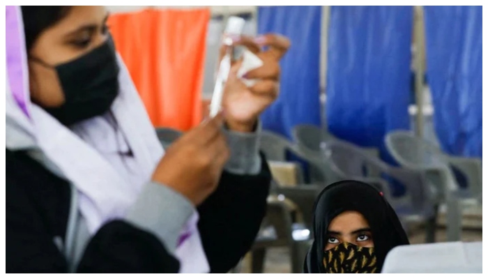 A girl waits as a healthcare worker prepares a dose of coronavirus disease (COVID-19) vaccine to administer at a vaccination centre in Karachi, Pakistan, January 21, 2022. — Reuters