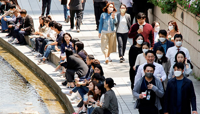 لوگ کورونا وائرس کی بیماری (COVID-19) کے پھیلاؤ کو روکنے کے لیے ماسک پہنتے ہیں جب وہ 3 مئی 2022 کو جنوبی کوریا کے شہر سیئول میں موسم بہار کے دھوپ والے دن چہل قدمی کرتے ہیں۔ – رائٹرز