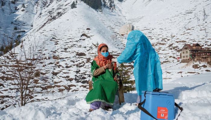 A healthcare worker from a clinic in North Kashmir braves freezing temperatures and snow to vaccinate people living in remote areas of India. — UNICEF.