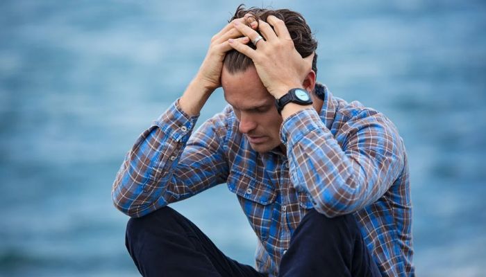 Man in blue and brown plaid dress shirt touching his hair. — Pexel