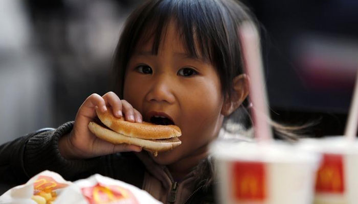 A child eats a hamburger outside a McDonalds fast food restaurant in downtown Milan. - Reuters/File