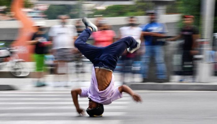 Venezuelan professional breakdance athlete Kenyer Mendez, 27, who has gone viral by performing a head slide trick to make a living dancing at Colombias traffic lights and dreams of joining Venezuelas first Olympic breakdance team in 2024, slides down a street headfirst at a traffic light, in Caracas, Venezuela June 22, 2022. — Reuters