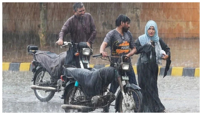 Commuters push their motorbikes along a street during a monsoon rainfall in Karachi on July 5, 2022. —AFP