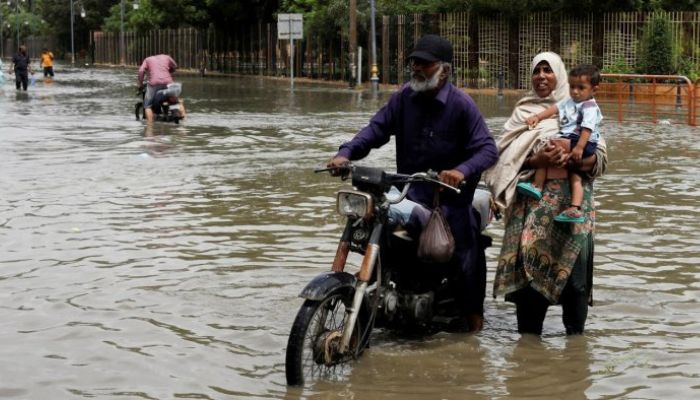 During the monsoon season in Karachi, a family wades through a flooded street.