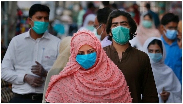 People wearing masks walk in a busy market place. — AFP/File