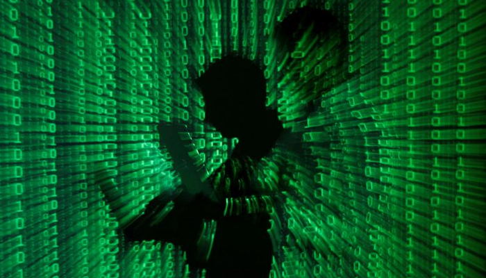 An illustration picture shows a projection of binary code on a man holding a laptop computer, in an office in Warsaw, on June 24, 2013. — Reuters