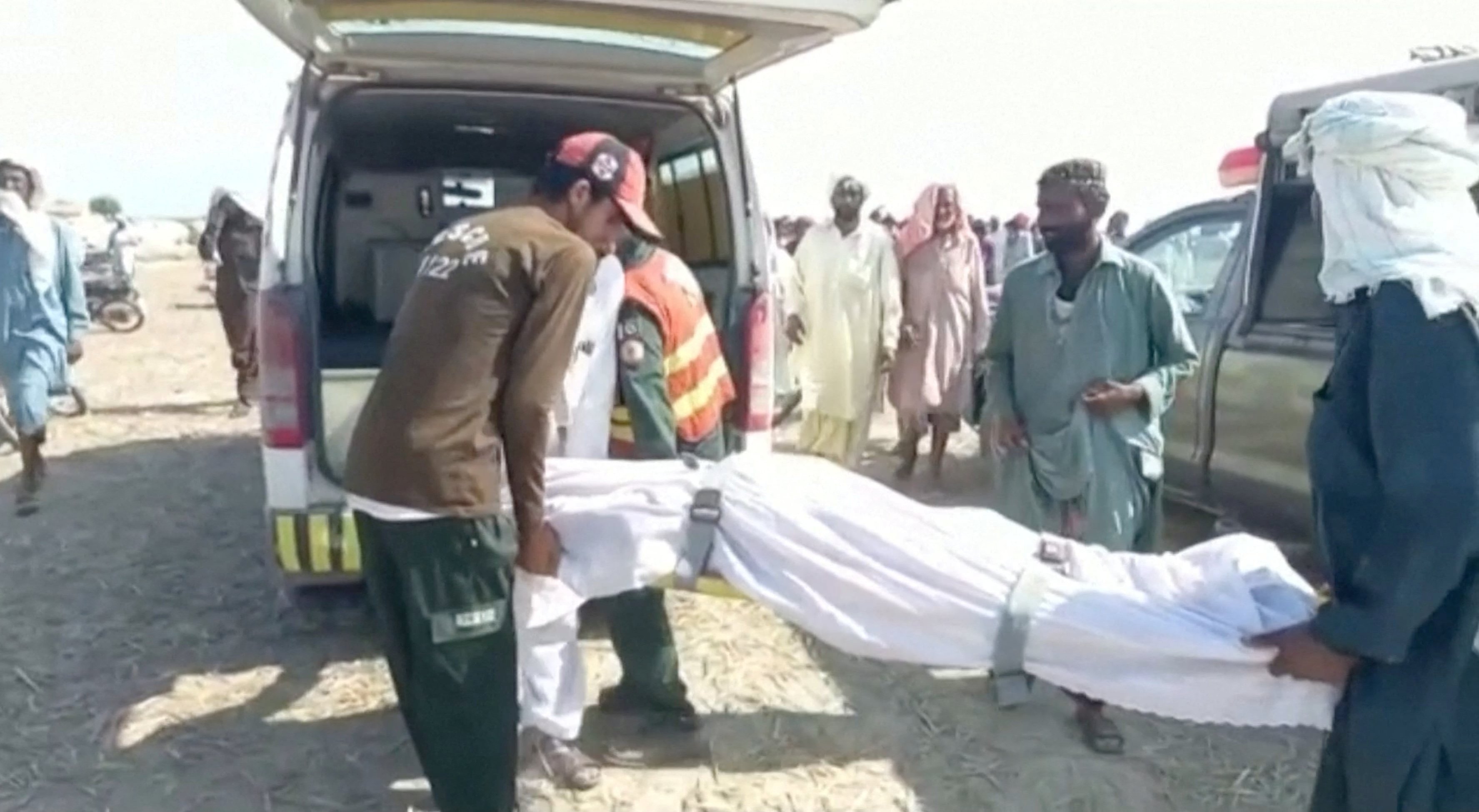 Locals carry a dead body covered in a white sheet to an ambulance, after a boat carrying around 100 people capsized in a central Pakistani river, in Sadiqabad, Pakistan, July 18, 2022, in this still image taken from a handout video. Punjab Government/Handout via REUTERS