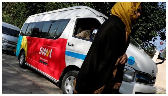 A woman walks past a vehicle with a logo of the Egyptian transport technology start-up Swvl, parked along a road in Islamabad, Pakistan, November 11, 2019. — Reuters/File