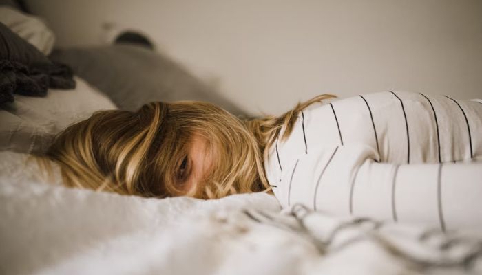 A woman lies on her front with her hair covering her face. —Unsplash