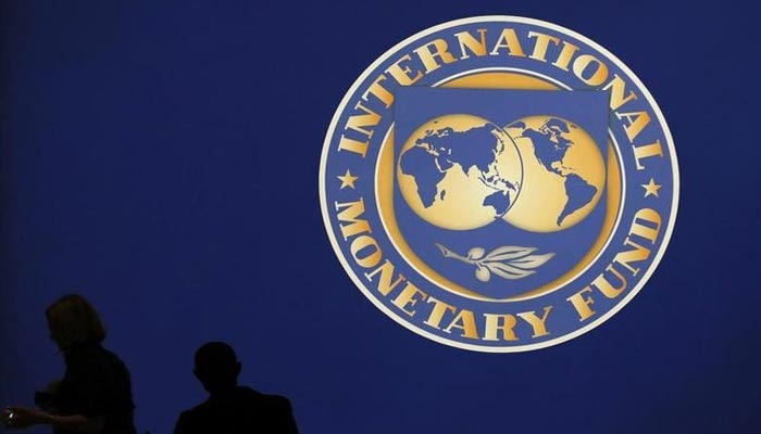 Visitors are silhouetted against the logo of the International Monetary Fund at the main venue for the IMF and World Bank annual meeting in Tokyo on October 10, 2012. — Reuters/File