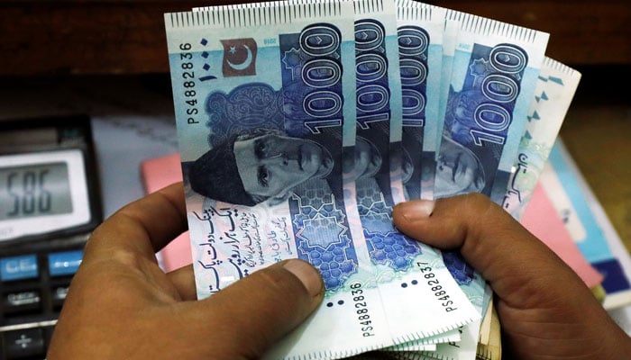 A trader counts rupee notes at a currency exchange booth in Pakistan in this undated photo. — Reuters/File