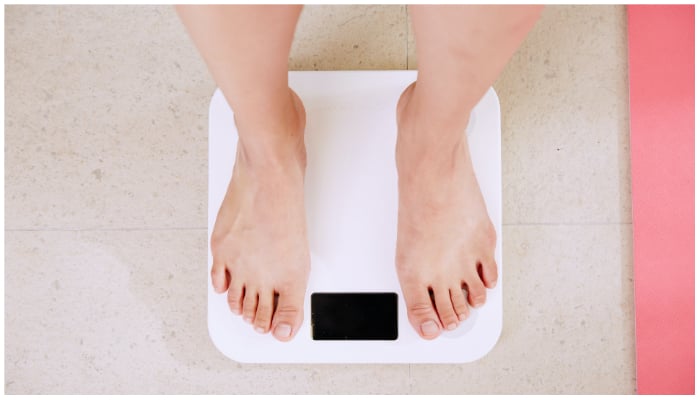 Representational image of a person standing on a weighing scale. —  Unsplash/ i yunmai