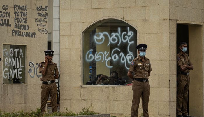 Policemen stand guard next to a graffitied wall following protests near the Presidents House, amid the countrys economic crisis, in Colombo, Sri Lanka July 21, 2022.— REUTERS/Adnan Abidi