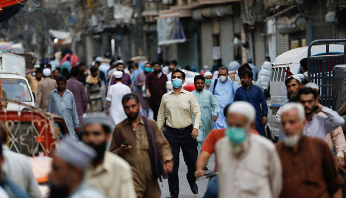 A man wears a protective face mask as he walks among other people along a street in Karachi, Pakistan June 16, 2020. — Reuters