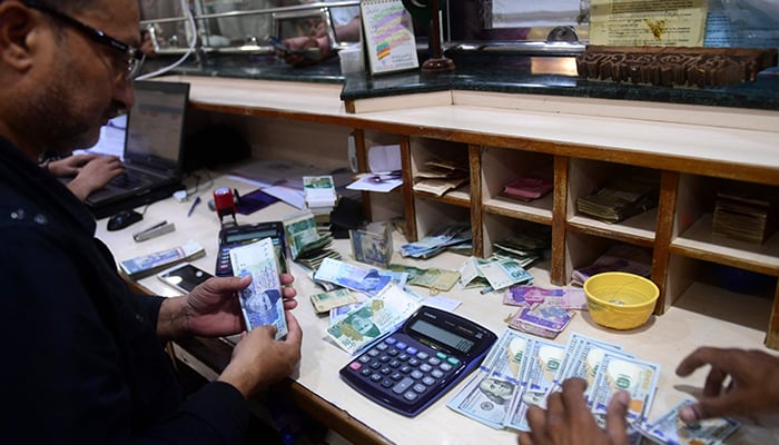 People exchange foreign currency at a shop in Karachi on April 7, 2022. — AFP