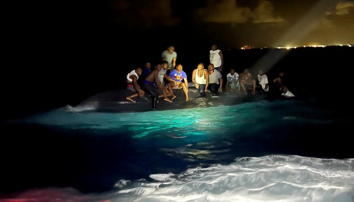 Survivors of a migrant boat that capsized perch on the overturned vessel off the coast of New Providence island, Bahamas July 24, 2022. —REUTERS