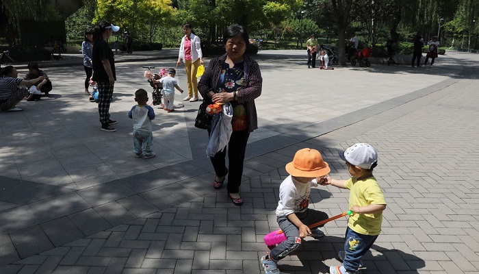Children play next to adults at a park in Beijing, China June 1, 2021. Photo: Reuters