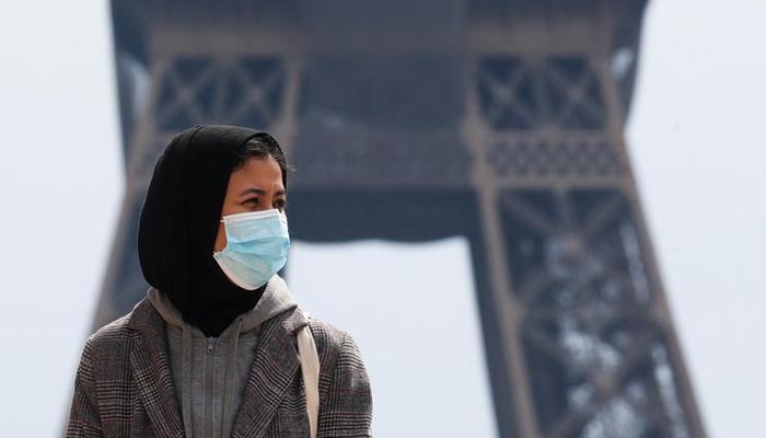 A woman, wearing a hijab and a protective face mask, walks at Trocadero square near the Eiffel Tower in Paris, France, on May 2, 2021. Picture was taken on May 2, 2021. — Reuters/File