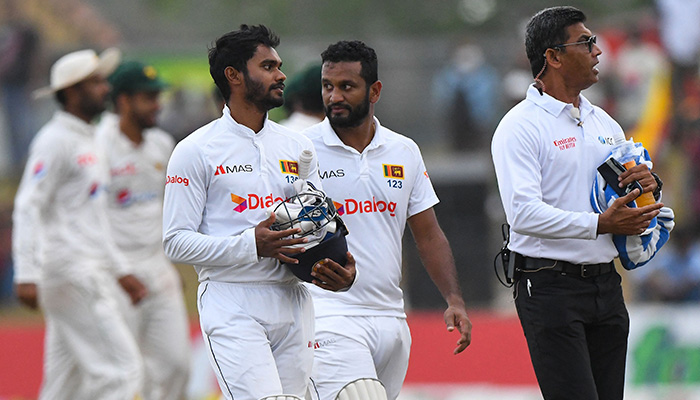 Sri Lankas Dhananjaya de Silva and captain Dimuth Karunaratne (C) walk back to the pavilion as the match gets delayed due to bad light during the third day of play of the second cricket Test match between Sri Lanka and Pakistan at the Galle International Cricket Stadium in Galle on July 26, 2022. — AFP