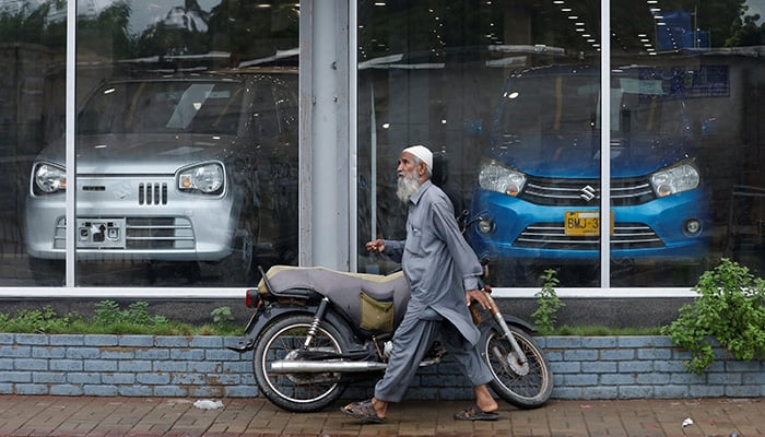 A man walks past a Suzuki outlet, displaying cars in Karachi, Pakistan, July 27, 2022. — Reuters