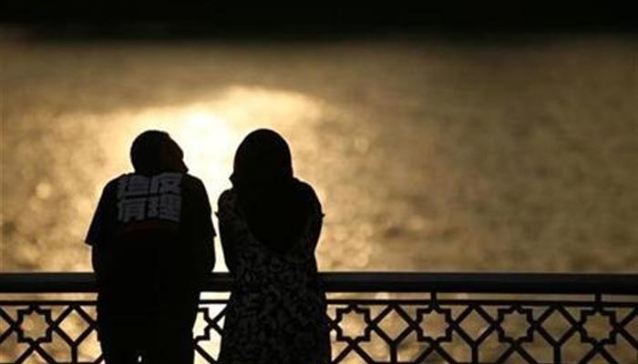 A couple watch a sunset near a lake in Putrajaya in this file photo. — Reuters/File