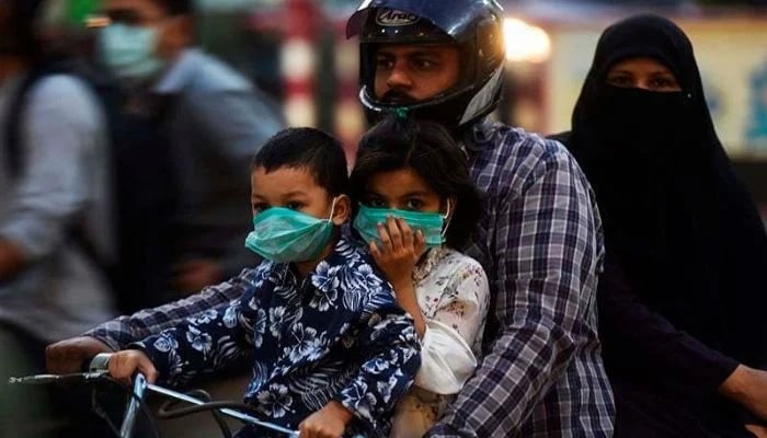 A family riding on a bike wear facemasks as a precaution against the coronavirus on October 29 in Karachi, — AFP/File