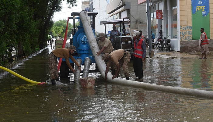 26 جولائی 2022 کو کراچی میں مون سون کی شدید بارشوں کے بعد فوجی سیلاب زدہ رہائشی علاقے سے پانی نکالنے کے لیے واٹر پمپ کا استعمال کر رہے ہیں۔ — اے ایف پی