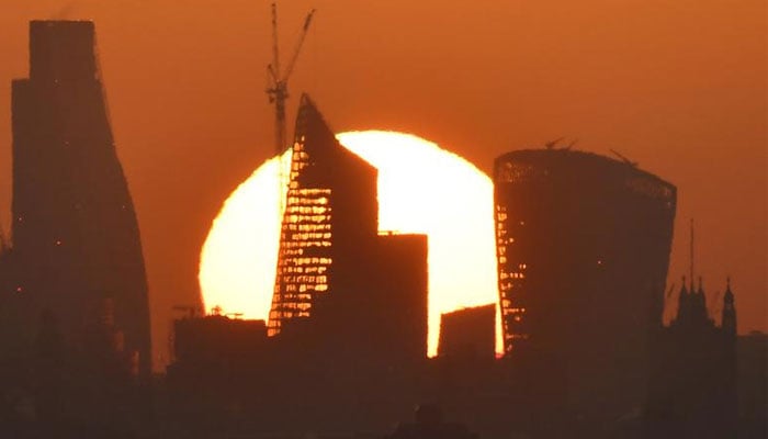 The sun is seen rising over skyscrapers in the City of London financial district in London, Britain.—Reuters