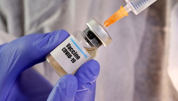 A woman holds a small bottle labeled with a Vaccine COVID-19 sticker and a medical syringe in this illustration taken April 10, 2020.—Reuters