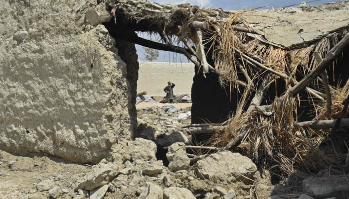 A villager stands beside his damaged house in the flooded area after the dam in Pishin district of Balochistan broke due to heavy rains on July 7, 2022. — AFP
