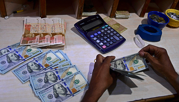 A foreign currency dealer counts US dollar notes at a currency market in Karachi on July 19, 2022. — AFP