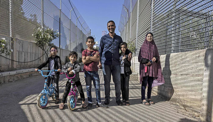 Palestinian Saadat Sabri Gharib is pictured with family members between Israeli army barriers, that lead to his house which is an enclave at the heart of the Jewish settlement of Givon Hahadasha, north of Jerusalem, bordering the West Bank Palestinian village of Beit Ijza, on 19 July 2022.—AFP