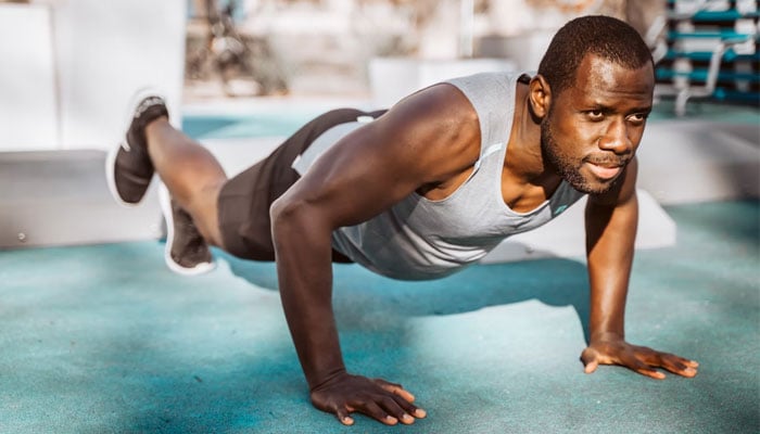 Fortune Vieyra working out and doing push-ups outdoors.—Unsplash