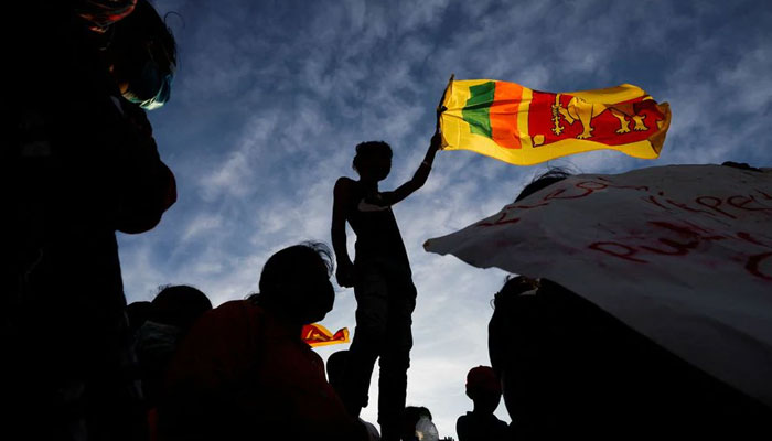 A demonstrator holding the Sri Lankan national flag stands during a protest against Sri Lankan President Gotabaya Rajapaksa, near the President's Secretariat, amid the country's economic crisis, in Colombo, Sri Lanka on April 15, 2022.  - Reuters