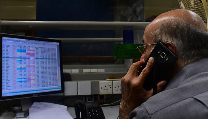 A stock broker can be seen speaking on call while looking at his screen. — AFP/File