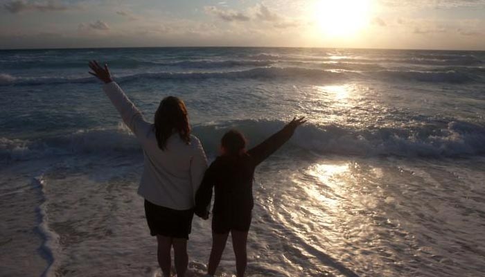 A mother and her daughter raise their hands on a beach at dawn on New Years Day in Cancun on January 1, 2012. — Reuters/File