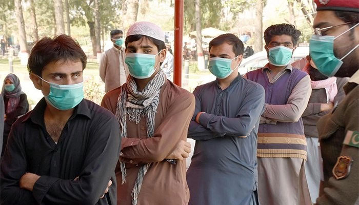 A file photo of people wearing masks stand in queue to receive COVID-19 shots. Photo: Geo.tv/ file