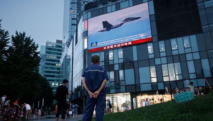 A man watches a CCTV news broadcast, showing a fighter jet during joint military operations near Taiwan by the Chinese Peoples Liberation Armys (PLA) Eastern Theatre Command, at a shopping center in Beijing, China, August 3, 2022. — Reuters