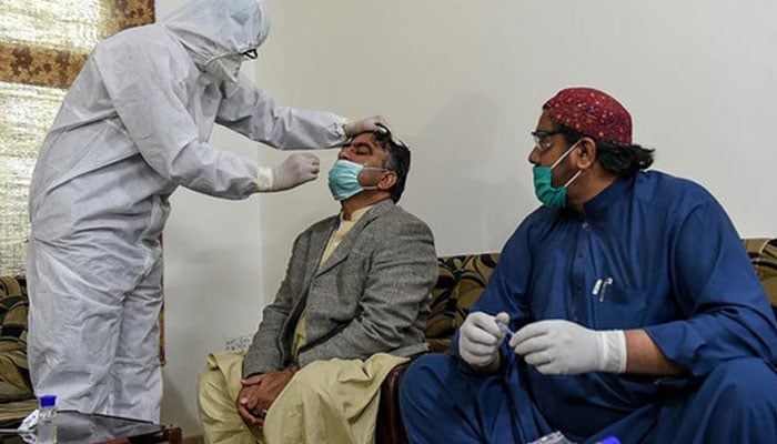 A health worker takes a testing sample from a journalist during a nationwide lockdown over the Covid-19 pandemic in Pakistan. Photo: AFP