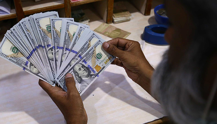 A foreign currency dealer counts US dollars at a money exchange company in Karahi, Pakistan, on 19 July 2022. — INP