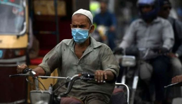 A man seen riding a motorcycle while wearing a facemask. Photo: AFP