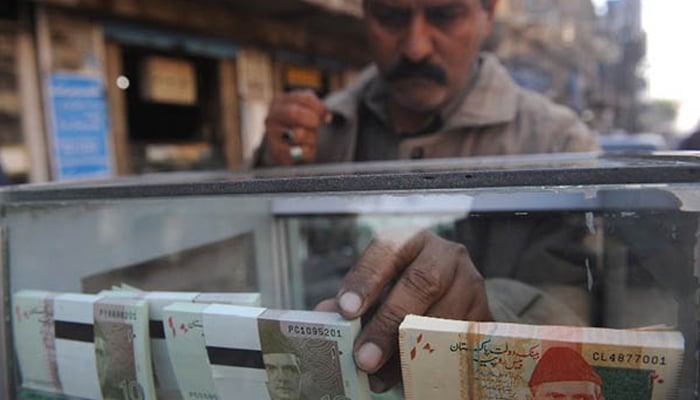 A trader places fresh notes on the counter in Pakistan. — AFP/File