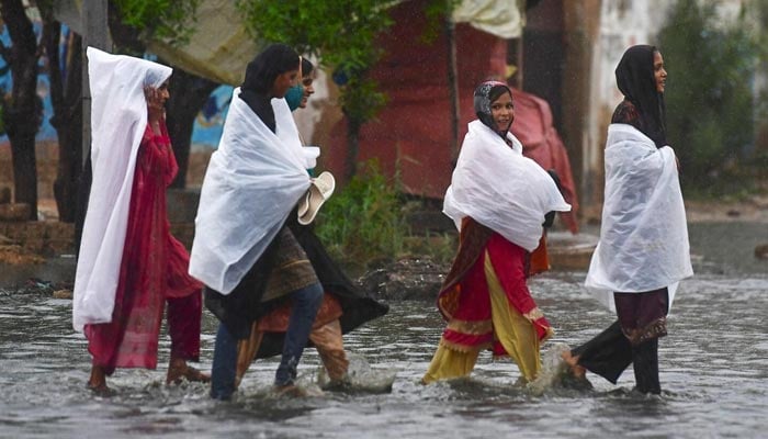 Women wade through a flooded street during a monsoon rainfall in Karachi on July 24, 2022. — AFP/File