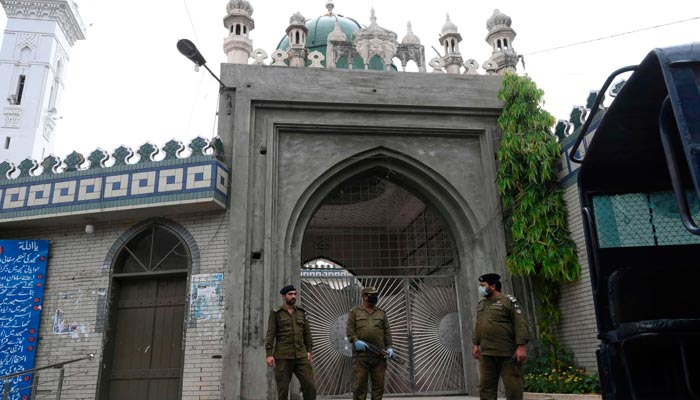 A representational image of policemen wearing facemasks stand guard outside a closed mosque in Lahore. — AFP/File