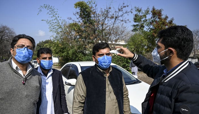 Man is seen checking the temperature of people. — AFP/File