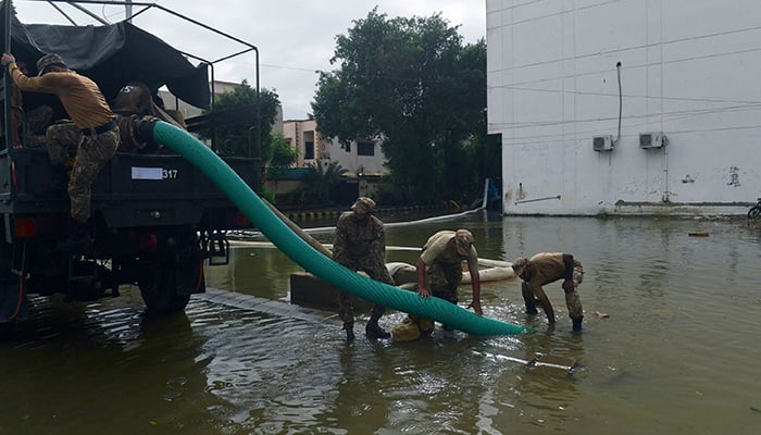 Troops use a water pump to remove water from a flooded residential area following heavy monsoon rains in Karachi on July 26, 2022. A weather emergency was declared in Karachi as heavier-than-usual monsoon rains continue to lash Pakistans biggest city, flooding homes and making streets impassable. — AFP