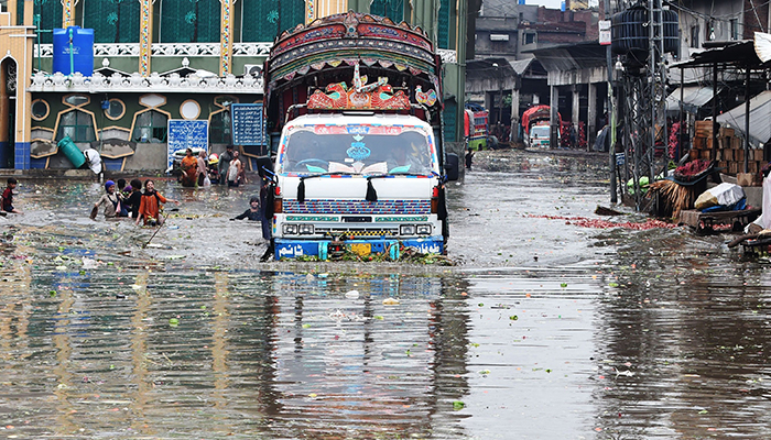 A truck drives down a flooded marketplace after heavy rainfall in Lahore on July 21, 2022. — AFP